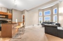 The property features a kitchen with wood cabinetry and black appliances, including a microwave and range - #418 392 Silver Berry Road Nw, Edmonton, AB  - Indoor 