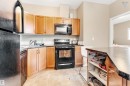 The kitchen features wood cabinetry, black appliances, and a kitchen island with storage - #418 392 Silver Berry Road Nw, Edmonton, AB  - Indoor Photo Showing Kitchen With Double Sink 