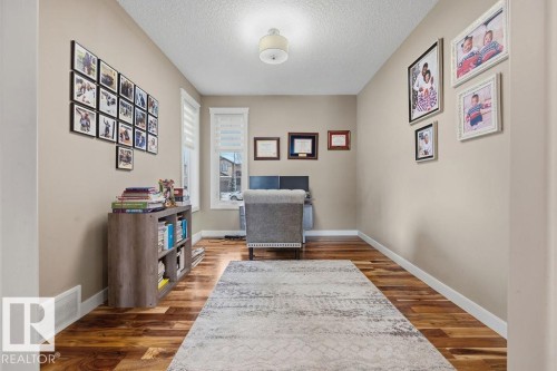 The room features hardwood floors, light neutral wall colors, and a ceiling light fixture - 76 Newgate Way, St. Albert, AB - Indoor Photo Showing Other Room