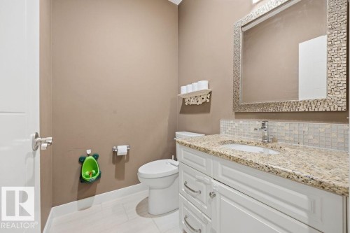 The bathroom features a vanity with a granite countertop, a white cabinet, and a tiled backsplash - 76 Newgate Way, St. Albert, AB - Indoor Photo Showing Bathroom