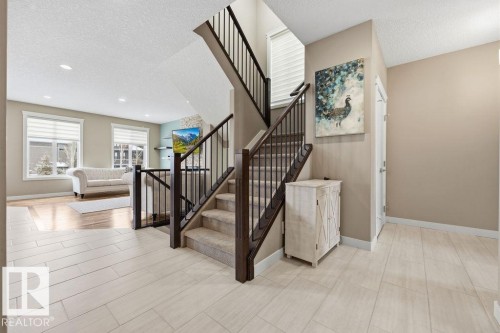 The property features a staircase with carpeted steps and dark wood handrails with iron balusters - 76 Newgate Way, St. Albert, AB - Indoor Photo Showing Other Room