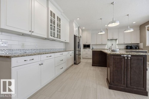 Well-appointed kitchen featuring white cabinetry, granite countertops, and a tiled backsplash - 76 Newgate Way, St. Albert, AB - Indoor Photo Showing Kitchen With Upgraded Kitchen