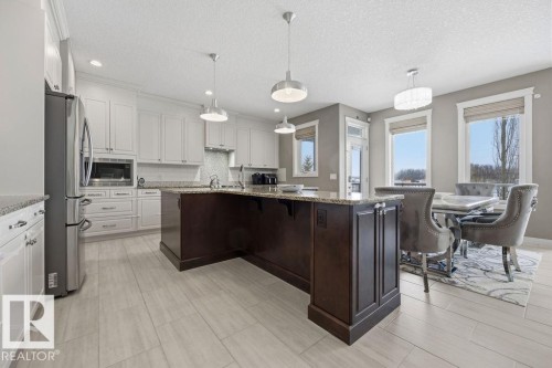 The kitchen features white cabinetry, stainless steel appliances, and a dark wood island with a granite countertop - 76 Newgate Way, St. Albert, AB - Indoor Photo Showing Kitchen With Upgraded Kitchen