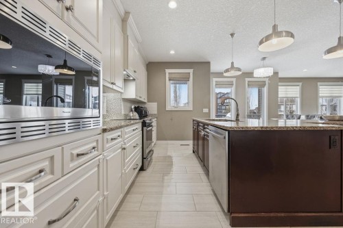 The kitchen features light-colored cabinetry with modern hardware, a built-in microwave, and stainless steel appliances - 76 Newgate Way, St. Albert, AB - Indoor Photo Showing Kitchen With Upgraded Kitchen