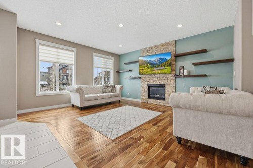 Living area featuring hardwood flooring, a fireplace with a stone surround, and recessed lighting - 76 Newgate Way, St. Albert, AB - Indoor Photo Showing Living Room With Fireplace