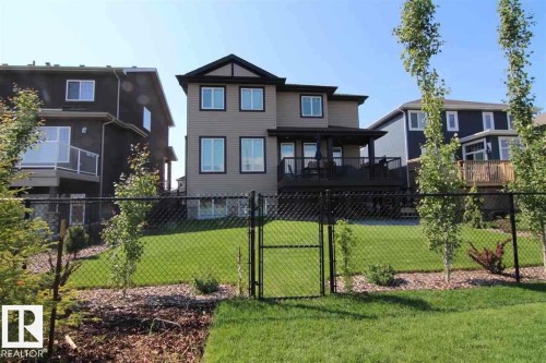 The property features a spacious backyard with a well-maintained lawn, a chain-link fence, and a wooden deck - 76 Newgate Way, St. Albert, AB - Outdoor With Deck Patio Veranda With Facade