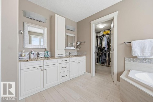 This bathroom features a double vanity with white cabinetry, granite countertops, and two framed mirrors - 76 Newgate Way, St. Albert, AB - Indoor Photo Showing Bathroom