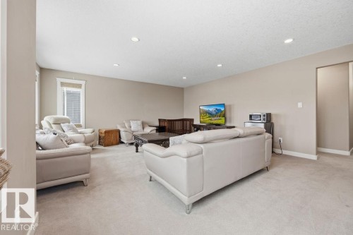 This inviting room features neutral-toned carpet flooring and recessed lighting - 76 Newgate Way, St. Albert, AB - Indoor