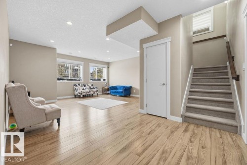 Spacious interior featuring hardwood flooring, recessed lighting, and a staircase with carpeting and a wooden handrail - 76 Newgate Way, St. Albert, AB - Indoor