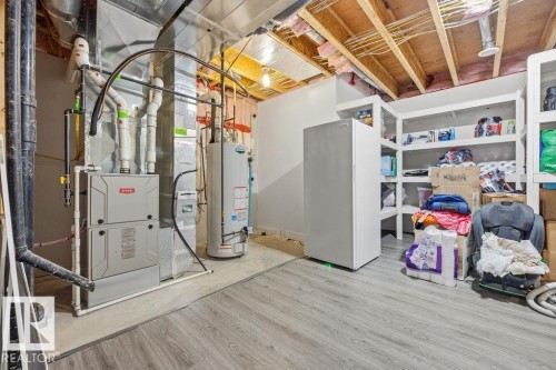The property includes a utility area with exposed ceiling joists, a water heater, and a furnace - 76 Newgate Way, St. Albert, AB - Indoor Photo Showing Basement