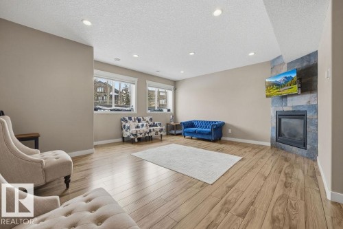 Living room featuring light wood flooring, recessed lighting, and a stone-clad fireplace - 76 Newgate Way, St. Albert, AB - Indoor Photo Showing Living Room With Fireplace