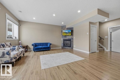 REC ROOM -Living area featuring hardwood flooring, recessed lighting, and a stone-clad fireplace - 76 Newgate Way, St. Albert, AB - Indoor Photo Showing Living Room With Fireplace
