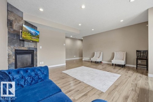 The property features a spacious living area with light-toned flooring, a stone-clad fireplace, and recessed lighting - 76 Newgate Way, St. Albert, AB - Indoor Photo Showing Living Room With Fireplace