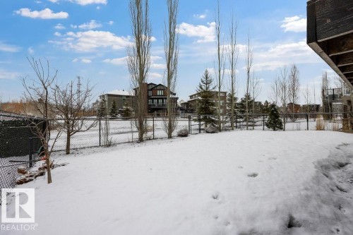 The property features a fenced yard, with a snow-covered lawn and various trees - 76 Newgate Way, St. Albert, AB - Outdoor