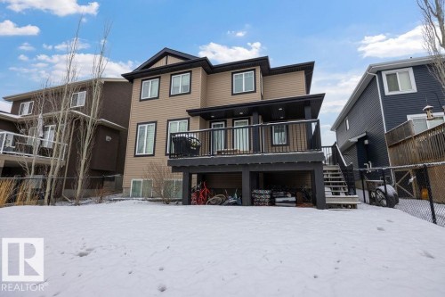 The property features a two-story exterior with light brown siding and dark trim, complemented by a raised deck with dark railings - 76 Newgate Way, St. Albert, AB - Outdoor