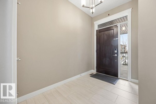 The entryway features a dark wood front door with a side light and a transom window, set against light-colored walls and light-toned tiled flooring - 76 Newgate Way, St. Albert, AB - Indoor Photo Showing Other Room