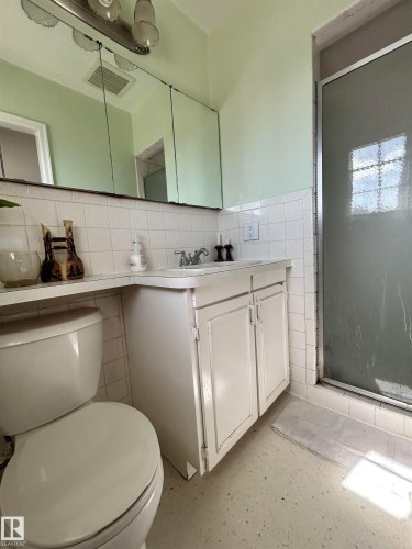 Bathroom featuring a white vanity with cabinet storage, a toilet, and a stand-up shower with a frosted glass door - 13112 63 Avenue, Edmonton, AB - Indoor Photo Showing Bathroom