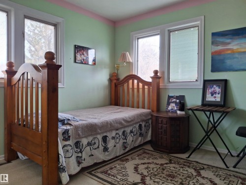 Room featuring two windows with white trim, light green walls, and a patterned area rug - 13112 63 Avenue, Edmonton, AB - Indoor Photo Showing Bedroom