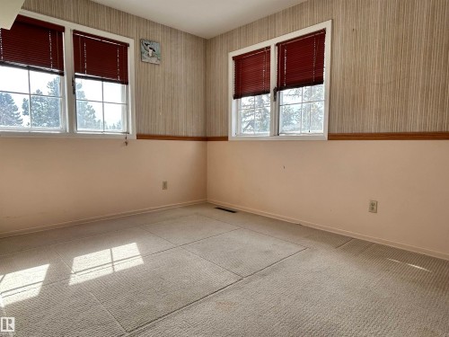 This room features two windows with blinds, providing natural light, and a textured wall covering with a chair rail - 13112 63 Avenue, Edmonton, AB - Indoor Photo Showing Other Room