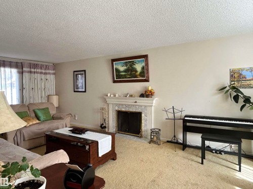 Living area featuring a fireplace with a light-colored mantel, light-toned walls, and carpeting - 13112 63 Avenue, Edmonton, AB - Indoor Photo Showing Other Room