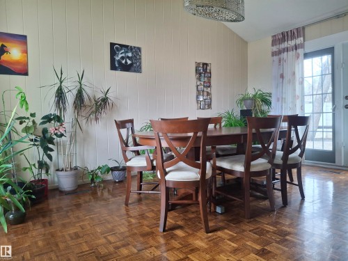 The dining area features wood flooring, a wood dining table with seating, and a vaulted ceiling - 13112 63 Avenue, Edmonton, AB - Indoor Photo Showing Dining Room