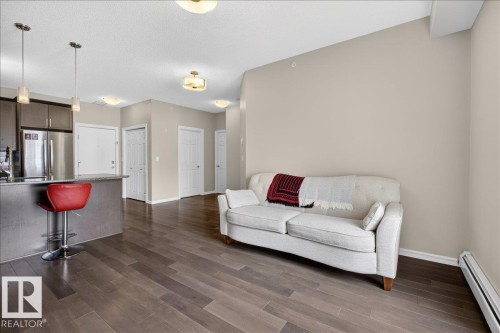 The property features hardwood floors, a kitchen island with pendant lighting, and stainless steel appliances - 413 2203 44 Avenue, Edmonton, AB - Indoor