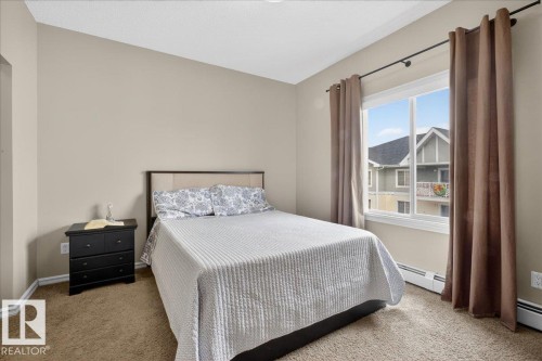 This room features a window with a view of external properties, neutral colored walls, and carpeted flooring - 413 2203 44 Avenue, Edmonton, AB - Indoor Photo Showing Bedroom