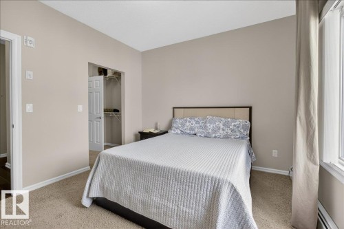 The bedroom features carpeted flooring, a window with curtains, and a built-in closet with a white door - 413 2203 44 Avenue, Edmonton, AB - Indoor Photo Showing Bedroom