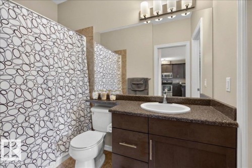 Bathroom featuring a vanity with a dark countertop and a white sink, a toilet, and a shower with a patterned curtain - 413 2203 44 Avenue, Edmonton, AB - Indoor Photo Showing Bathroom