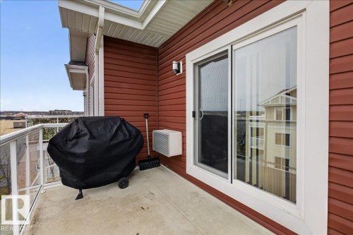 The property includes a private balcony with a concrete floor, glass and white railings, and a red exterior wall - 413 2203 44 Avenue, Edmonton, AB - Outdoor With Exterior