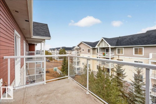 The property features a concrete balcony with glass railings, providing an open view of the surrounding community - 413 2203 44 Avenue, Edmonton, AB - Outdoor