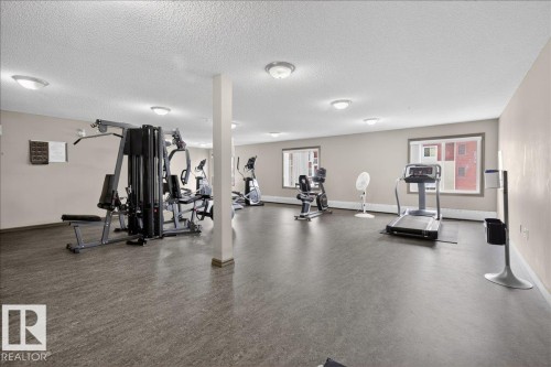 The property features a dedicated fitness area with cardio and weight training equipment - 413 2203 44 Avenue, Edmonton, AB - Indoor Photo Showing Gym Room