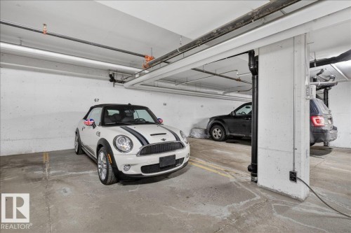The property includes dedicated parking spaces within a concrete garage, featuring overhead piping and structural columns - 413 2203 44 Avenue, Edmonton, AB - Indoor Photo Showing Garage