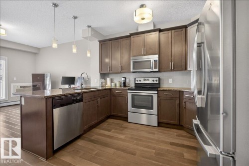 The kitchen features stainless steel appliances, including a refrigerator, microwave, and range - 413 2203 44 Avenue, Edmonton, AB - Indoor Photo Showing Kitchen With Stainless Steel Kitchen With Upgraded Kitchen