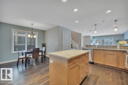 Bright kitchen and dining area featuring hardwood flooring, recessed lighting, and a kitchen island with a granite countertop - 9540 142 Street, Edmonton, AB - Indoor
