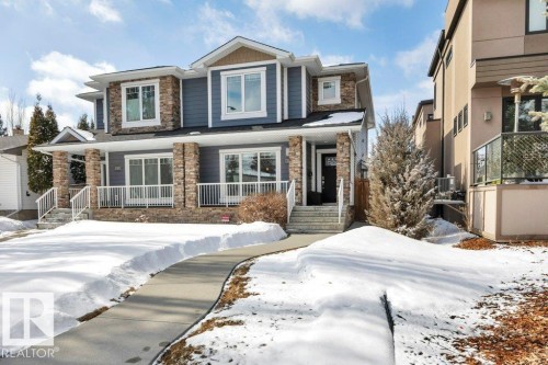 The property features a stone and siding exterior, a front porch with white railings, and a concrete pathway leading to the entrance - 9540 142 Street, Edmonton, AB - Outdoor With Facade