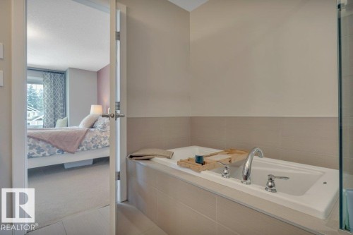 This bathroom features a  bathtub with sleek chrome fixtures and neutral-toned wall tiles, offering a tranquil space - 9540 142 Street, Edmonton, AB - Indoor Photo Showing Bathroom