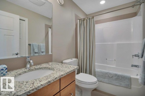 The bathroom features a vanity with a granite countertop and an undermount sink, a toilet, and a bathtub with a shower - 9540 142 Street, Edmonton, AB - Indoor Photo Showing Bathroom