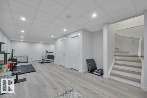 This expansive recreation room features light-toned flooring, recessed lighting, and a staircase with light-toned treads - 9540 142 Street, Edmonton, AB - Indoor