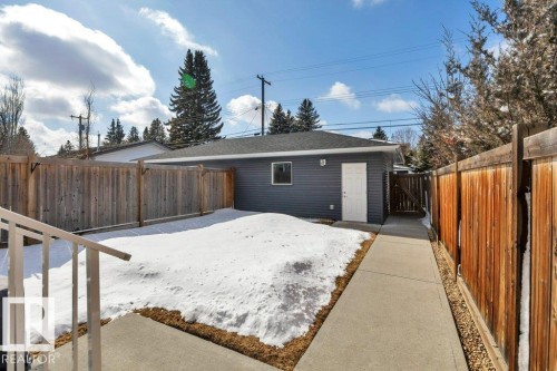 Detached double garage with dark grey siding, a white entry door, and a concrete pathway - 9540 142 Street, Edmonton, AB - Outdoor