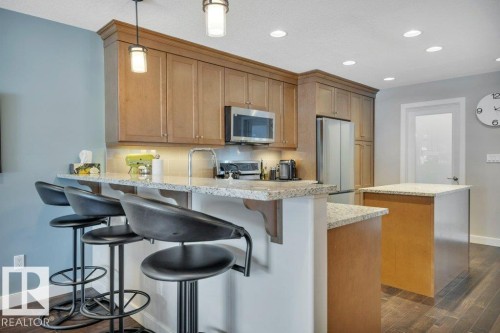 The kitchen features warm wood cabinets to the ceiling, stainless steel appliances, and granite countertops - 9540 142 Street, Edmonton, AB - Indoor Photo Showing Kitchen With Upgraded Kitchen