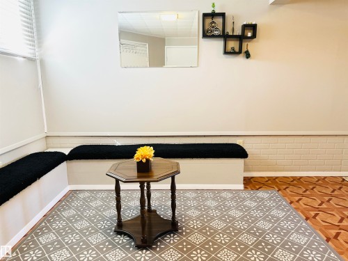 This room features a built-in bench seating area, patterned flooring, and a decorative wall mirror - 15 Pinecliff Close Ne, Calgary, AB - Indoor Photo Showing Other Room