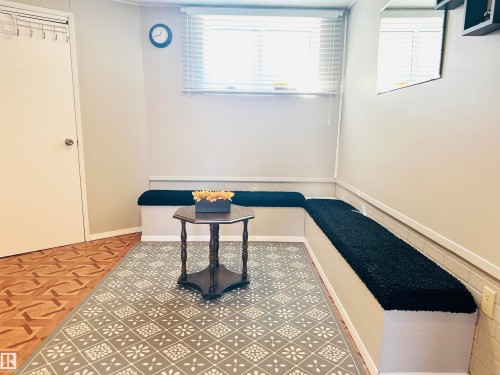 This room features built-in bench seating with dark cushions, a window with blinds, and light-colored walls - 15 Pinecliff Close Ne, Calgary, AB - Indoor Photo Showing Other Room