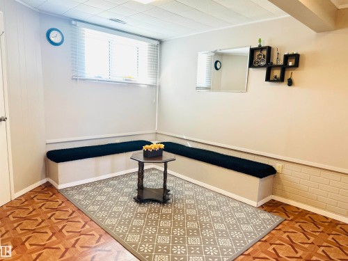 This inviting space features a window with blinds, built-in bench seating, and patterned flooring - 15 Pinecliff Close Ne, Calgary, AB - Indoor Photo Showing Other Room