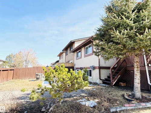 The property features a brown wooden fence, a deck with stairs, and a stucco exterior - 15 Pinecliff Close Ne, Calgary, AB - Outdoor