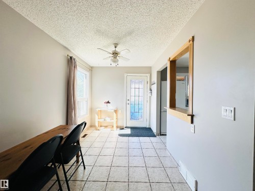 This area features tile flooring, a ceiling fan, and a pass-through window with a wood frame - 15 Pinecliff Close Ne, Calgary, AB - Indoor Photo Showing Other Room