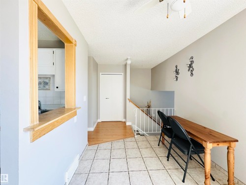 This area features light-colored walls and a tiled floor, with a section of wood flooring visible near the white door - 15 Pinecliff Close Ne, Calgary, AB - Indoor Photo Showing Other Room