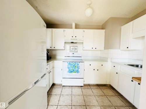 The kitchen features white cabinetry, a white tile backsplash, and a tiled floor - 15 Pinecliff Close Ne, Calgary, AB - Indoor Photo Showing Kitchen