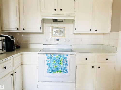Well-maintained kitchen featuring white cabinetry, a white electric range, and light-colored countertops - 15 Pinecliff Close Ne, Calgary, AB - Indoor Photo Showing Kitchen