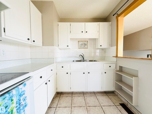 The kitchen features white cabinetry, a double basin sink, and tile flooring - 15 Pinecliff Close Ne, Calgary, AB - Indoor Photo Showing Kitchen With Double Sink